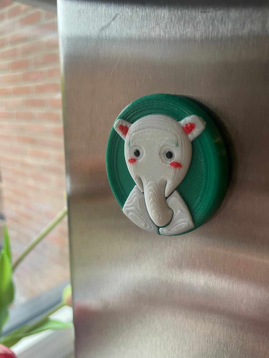 3D-geprinte koelkastmagneet van een olifant met een groene achtergrond.